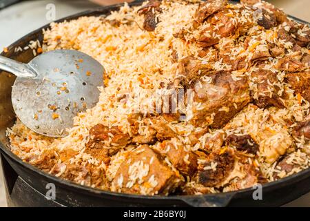 Gustosa Uzbek pilaf in un calderone sul fuoco in aria aperta a street food festival Foto Stock