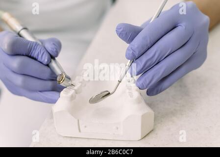 Il dentista tiene un trapano con un impianto. Primo piano di uso di trapano dentale per i denti del paziente in ufficio odontoiatrico in una procedura di trattamento dentale. Foto Stock