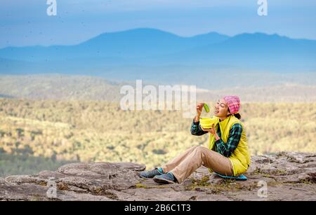 Donna escursionista mangiare il pasto da piatto durante il campeggio in montagna Foto Stock