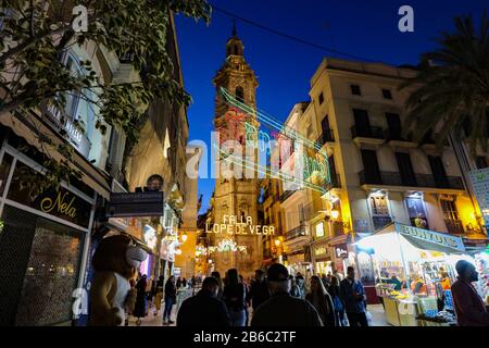 Strada illuminata per il festival Fallas 2020 che è stato annullato per prevenire la diffusione del coronavirus, con la chiesa di Santa Catalina sullo sfondo. Foto Stock