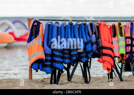 Gruppo di giubbotti di salvataggio o giubbotti di salvataggio appesi sulle pareti della stazione di navigazione contro la costa del mare Foto Stock