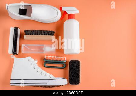 Prodotti per la pulizia delle scarpe su sfondo arancione Foto Stock