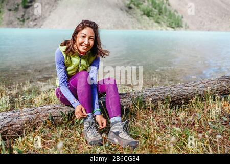 una donna turistica collega le sue scarpe con scarponi da trekking e calzature per esterni Foto Stock