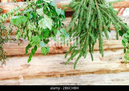 Scope di betulla e larice appese sul portico di legno del bagno rurale di campagna Foto Stock