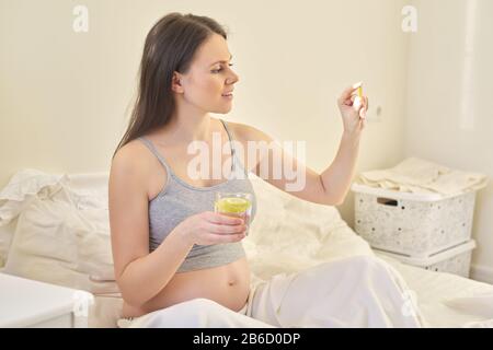 Giovane donna incinta che prende le vitamine. A, D, e, omega-3 capsule Foto Stock