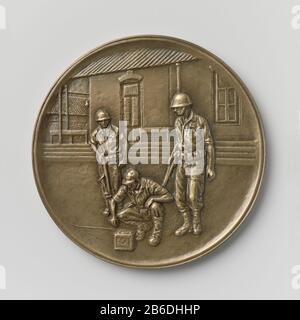 Zucchero di liberazione Djatiroto 22 luglio 1947 Bronzen penning in blauw doosje. Voorzijde: Drie mariniers, de voorste gehurkt bij een accu. De beide andere figuren stean, met het geweer in aanslag, naast de eerste. Op de achtergrond het amministraegebouw van de suikerfabriek. Deze voorstelling is ontleend aan een schilderij voorstellende het ogenblik, Foto Stock