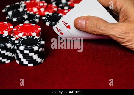 Una mano caucasica maschile Che Mostra Una Coppia di assi nel buco, Cuori e diamanti, un mazzo standard rosso e bianco di carte con il poker di argilla rossa e nera ch Foto Stock