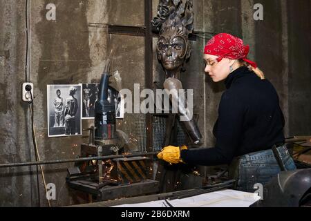 Perm, Russia – 06 marzo 2020: Donna artista del metallo al lavoro in officina con sega metallica Foto Stock