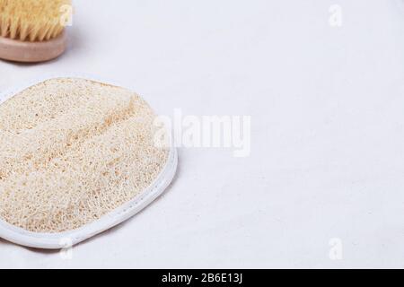 Un guanto in spugna per massaggio luffa o luffah per esfoliazione della pelle su un tessuto di cotone organico beige con spazio per le copie Foto Stock