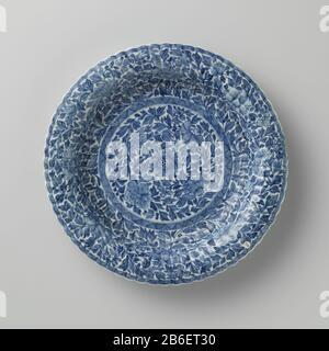 Piatto con parete a coste e motivo floreale continuo Bord van porselein ha incontrato geribde wand en geschulpte rand, beschilderd in onderglazuur blauw. Op het plat bloemranken in een medaillon met een band arceerwerk; de wand met bloemranken en een band met arceerwerk; de achterzijde met vier lotusplanten. Gemerkt op de onderzijde met een ruit in een dubbele cirkel. Rand beschadigd. Blauw-wit. Produttore : pottenbakker: AnoniemPlaats fabbricante: China Dating: CA. 1700 - ca. 1724School / stijl: Periode di Qianlong (1736-1795) / periode di Kangxi (1662-1722) / periode di Yongzheng (1723-1735) Foto Stock