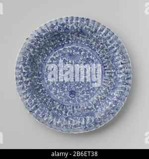 Piatto con parete a coste e motivo floreale continuo Bord van porselein ha incontrato geribde wand en geschulpte rand, beschilderd in onderglazuur blauw. Op het plat bloemranken in een medaillon met een band arceerwerk; de wand met bloemranken en een band met arceerwerk; de achterzijde met vier lotusplanten. Gemerkt op de onderzijde met een ruit in een dubbele cirkel. Een barst in de rand. Blauw-wit. Produttore : pottenbakker: AnoniemPlaats fabbricante: China Dating: CA. 1700 - ca. 1724School / stijl: Periode di Qianlong (1736-1795) / periode di Kangxi (1662-1722) / periode di Yongzheng (1723-1735) Foto Stock