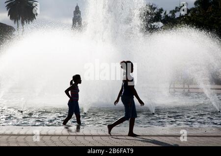 Silhouette di due ragazze che camminano davanti alle fontane d'acqua Foto Stock