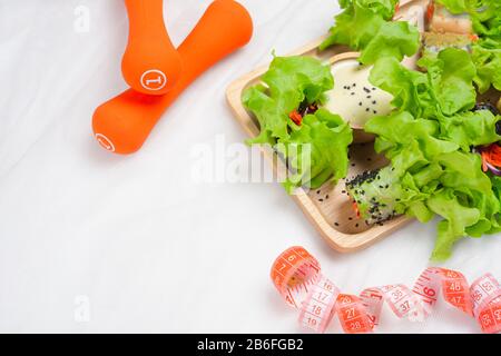 Fitness, insalata fresca sana, dieta e stili di vita attivi, perdita di peso e concetto detox. Dieta alimentare, metro a nastro, dumbbells su sfondo bianco, top v Foto Stock