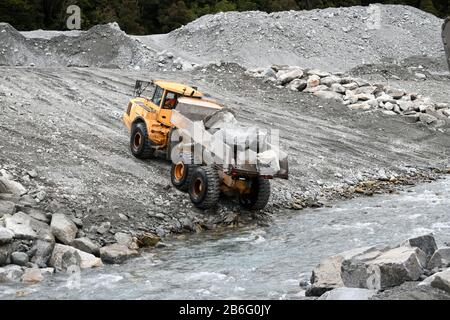 Otira, NUOVA ZELANDA, 19 SETTEMBRE 2019: Un camion punta scarica un carico di roccia per creare il controllo delle acque alluvionali su un fiume della costa occidentale appena sopra una brid ferroviaria Foto Stock