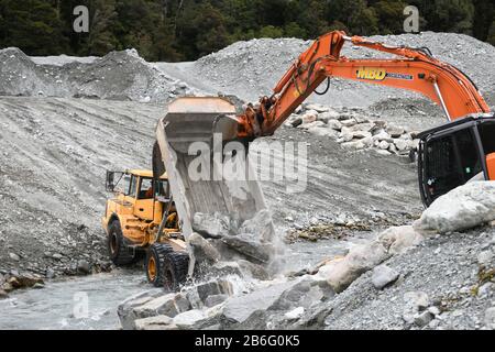 Otira, NUOVA ZELANDA, 19 SETTEMBRE 2019: Un camion punta scarica un carico di roccia per creare il controllo delle acque alluvionali su un fiume della costa occidentale appena sopra una brid ferroviaria Foto Stock