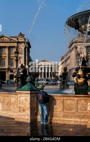 Vita quotidiana a Parigi: Ragazzo guardando fontana a Place de la Concorde in un pomeriggio feriale, Riva Destra, Parigi, Francia, Europa, colore Foto Stock