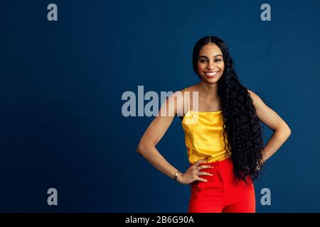 Ritratto di una giovane donna felice con capelli ricci neri molto lunghi sorridenti con le braccia in vita Foto Stock