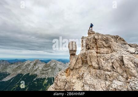 Alpinista si erge su una roccia, crinale della catena Oedkarspitzen, Hinterautal-Vomper, Karwendel, Tirolo, Austria Foto Stock