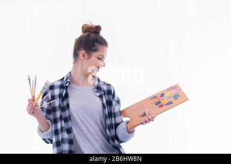 Artista donna che tiene pennelli guardando tavolozza pittore Foto Stock