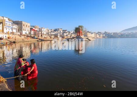 Pellegrini indù che camminano e pregano vicino al lago santo in Pushkar, India. Pushkar è una città dell'Ajmer nello stato del Rajasthan. Foto Stock