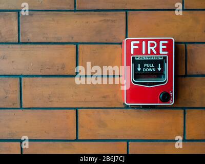 Sistema di sicurezza con allarme antincendio manuale rosso. Postazione pull o call point, attivazione manuale allarme incendio su sfondo muro in mattoni con spazio di copia. Foto Stock