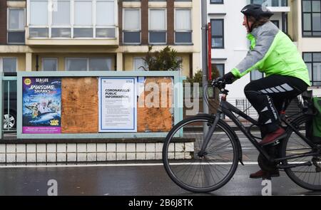 Brighton UK 11th Marzo 2020 - un pendolari di mattina presto su un pass per le bici da un NHS Coronavirus informazione sul lungomare di Brighton . Credito: Simon Dack / Alamy Live News Foto Stock