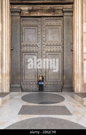 I turisti cercano di vedere l'interno del Pantheon, le cui famose porte sono state chiuse al pubblico come parte delle precauzioni Coronavirus a Roma, Italia Foto Stock