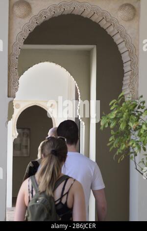 I turisti visitano gli archi Nasrid nelle porte del palazzo musulmano di Alcazaba, Malaga, Spagna Foto Stock