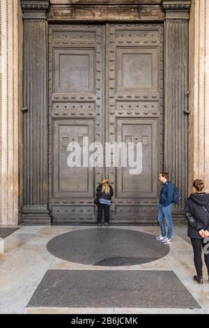 I turisti cercano di vedere l'interno del Pantheon, le cui famose porte sono state chiuse al pubblico come parte delle precauzioni Coronavirus a Roma, Italia Foto Stock
