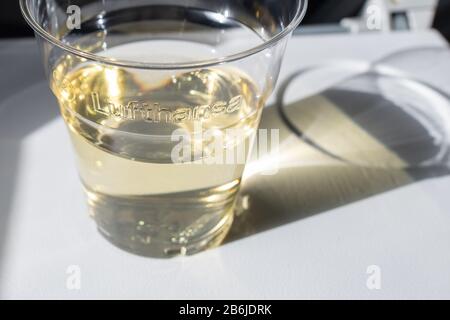 Vino bianco in tazza di plastica sul volo Lufthansa Foto Stock