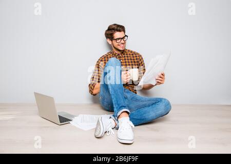 Bell'uomo in occhiali seduti a pavimento e in contratto di lettura Foto Stock