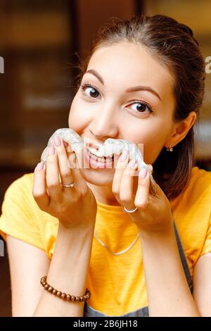 Funny brunette donna chef o casalinga in grembiule con gamberi crudi tigre in mano Foto Stock