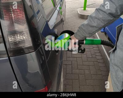 Close-up foto della mano che tiene la pompa del combustibile e il rifornimento di auto alla stazione di benzina Foto Stock