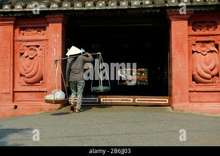 venditore di strada che arriva in un ponte nella strada di hoi an-vietnam Foto Stock