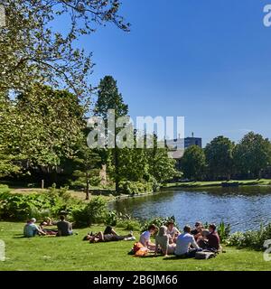 Città di Leiden, provincia dell'Olanda meridionale, Paesi Bassi, Europa - nel giardino botanico le persone si rilassano al bordo del canale Moresigel , l'Hortus botanicus Leiden è il più antico giardino botanico dei Paesi Bassi. Il Giardino di Clusius dà un'impressione di ciò che l'Hortus era come intorno al 1600 la più antica settiodel Hortus, risalente al 1590, la città di Leiden è conosciuta per la sua architettura secolare, i suoi canali, la sua universitof 1590, il nativitof Rembrand, La città dove fiorì il primo tulipano bulof in Europa nel 16 ° secolo Foto Stock