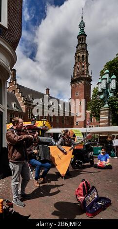 Città di Leiden, provincia dell'Olanda meridionale, Olanda, Europa - i musicisti di strada animano il mercato domenicale di fronte allo stile rinascimentale. orologio e campanile del Municipio Foto Stock