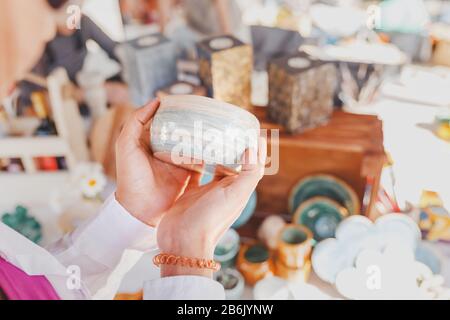 donna che seleziona vasellame di ceramica nel mercato delle pulci Foto Stock