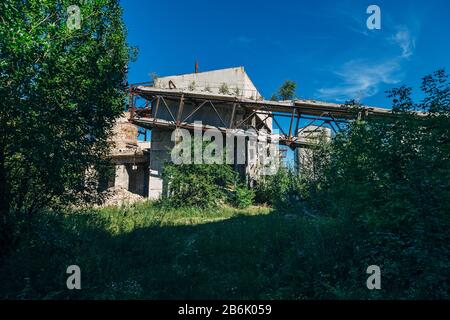 Vecchia fabbrica abbandonata overgrown di cemento armato. Foto Stock