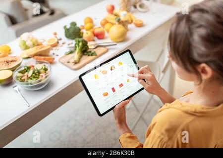 Donna che acquista cibo online utilizzando un tablet digitale in cucina. Concetto di acquisto online tramite dispositivi mobili Foto Stock