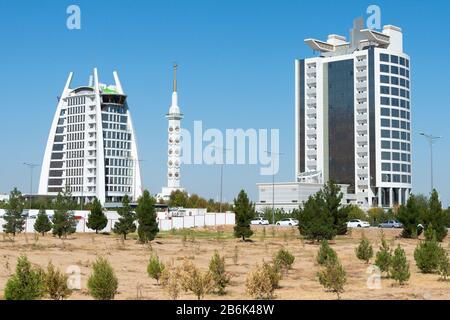 Due edifici ministeri in marmo bianco con il Monumento della Costituzione tra ad Ashgabat, Turkmenistan. Costruzioni di marmo bianco del governo. Foto Stock
