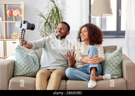 blogging, videoblog e people concept - happy african american coppia di video blogger con videocamera videoblogging a casa Foto Stock