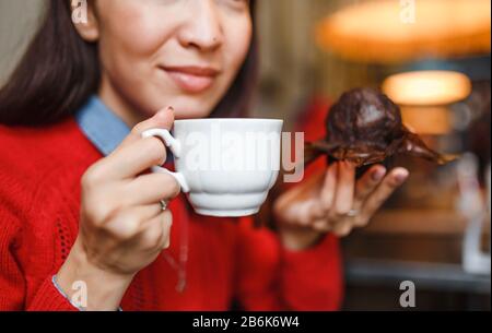 donna bevendo caffè e mangiando una deliziosa torta di muffin nel moderno caffè della città Foto Stock