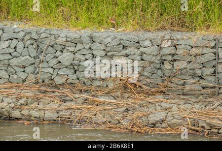 Gabion pareti di contenimento per controllare l'erosione e le inondazioni sulle rive di un fiume che scorre veloce Foto Stock