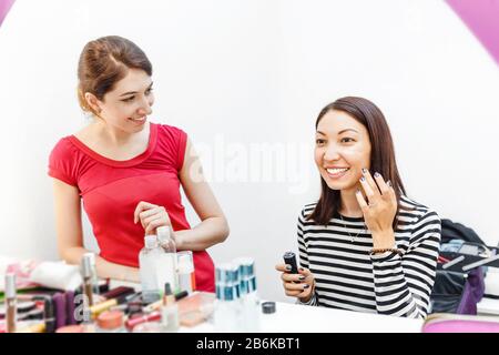 Due donne che usano la crema cosmetica prima di fare il trucco Foto Stock