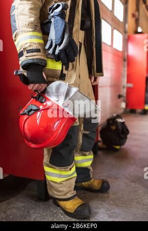 Casco rosso in mano al pompiere Foto Stock