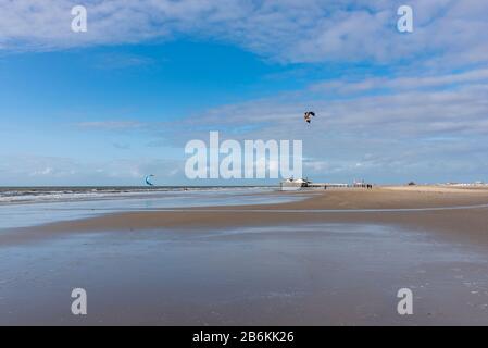 Spiaggia con palafitte e kite surfisti, Sankt Peter-Ording, Mare del Nord, Schleswig-Holstein, Germania, Europa Foto Stock