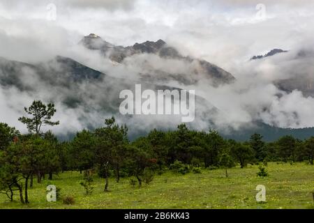 Jade Dragon Snow Mountain, Yulong Xueshan, che si infrangono tra nuvole e nebbia a Lijiang, provincia di Yunnan, Cina. I ghiacciai possono essere visti tutto l'anno. Foto Stock