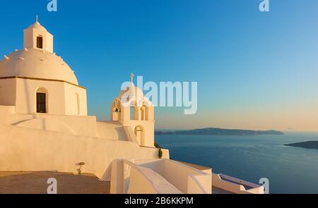 Chiesa greca sulla scogliera dell'isola di Santorini vicino al mare al tramonto, Grecia -- Paesaggio Foto Stock