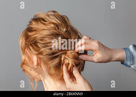 Closeup parrucchiere vista posteriore coiffeur rende l'acconciatura al salone di bellezza Foto Stock