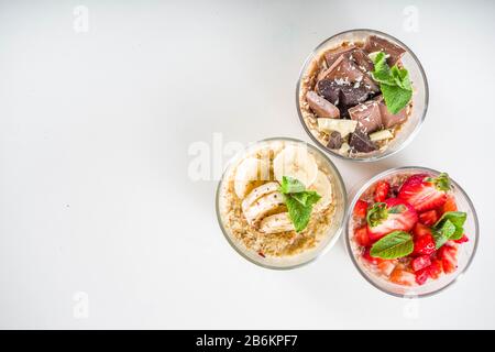 Set vari frutta durante la notte farinata d'avena. Porridge di avena con fragola, banane, cioccolato, noci in piccoli vasi porzione. Colazione estiva con farinata d'avena. Sano Foto Stock